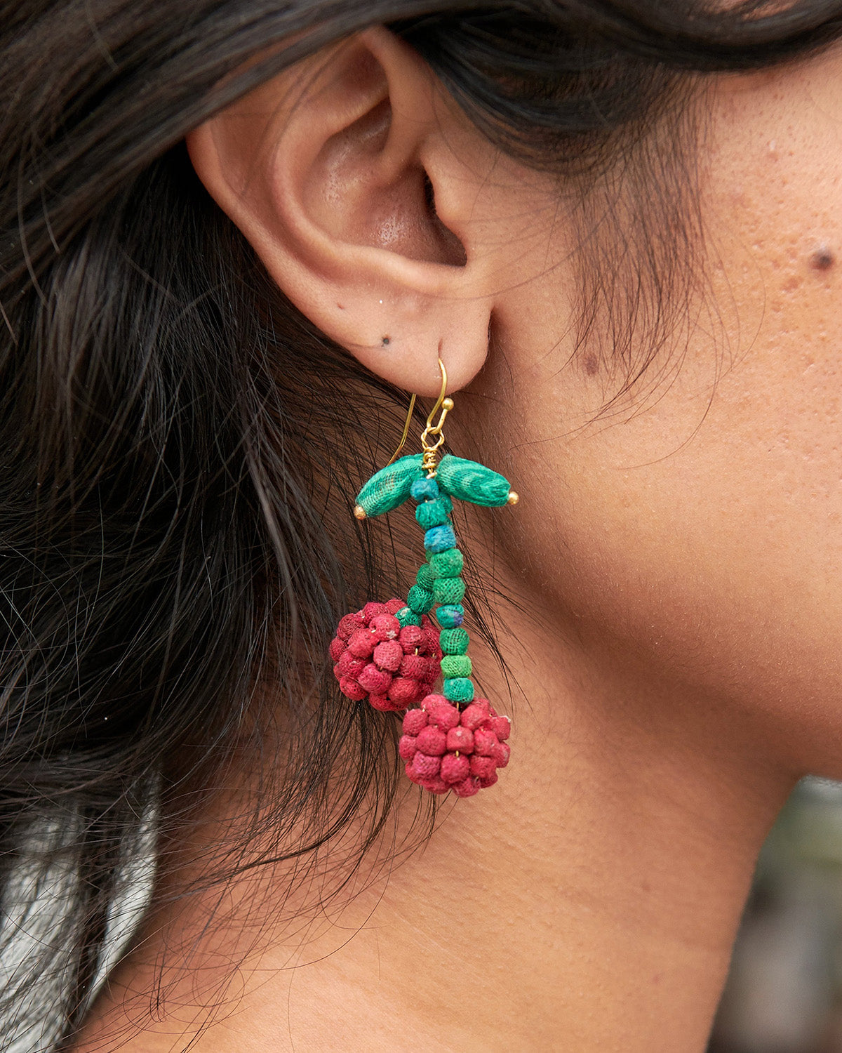 Teal beaded drop earrings with gold hooks and red pom-pom berry clusters.