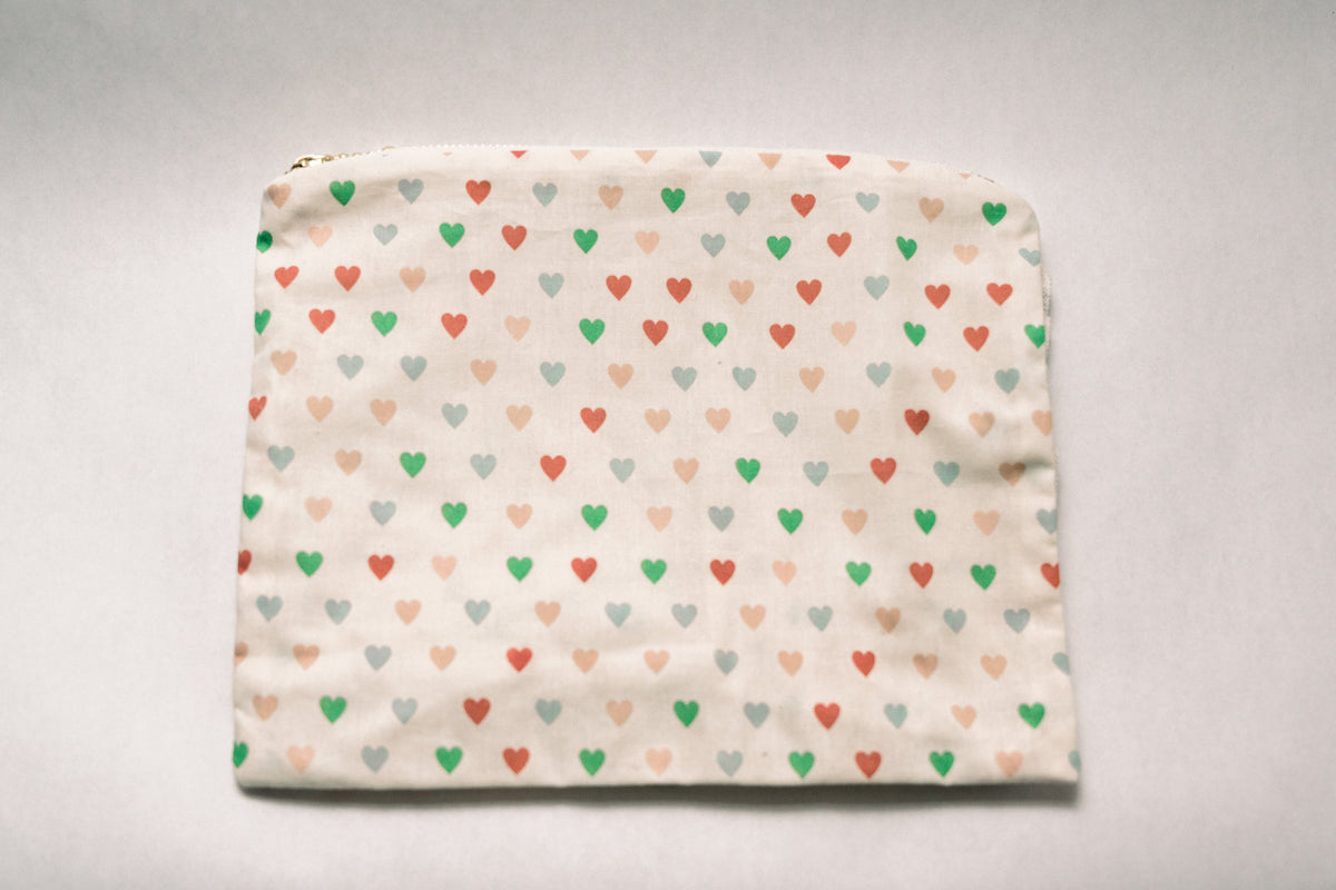 White heart-print zipper pouch with gold zipper, flat rectangle