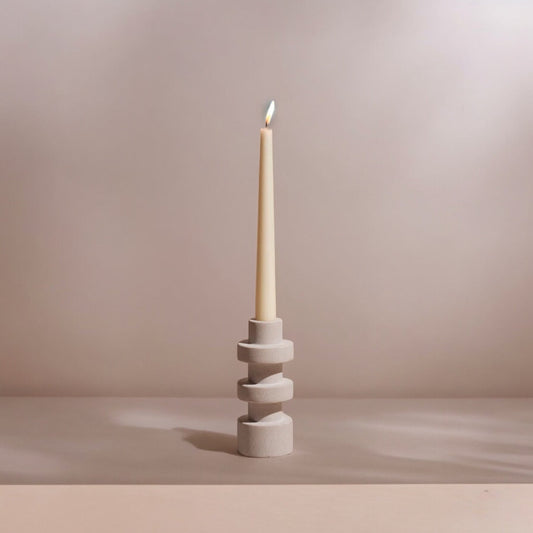 Stacked cylindrical candle holder with a white pillar candle and lit wick.