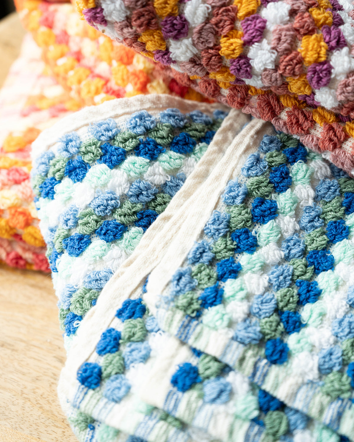Close-up of checkered hand towel in blue and mint tones with textured weave, no tassels.
