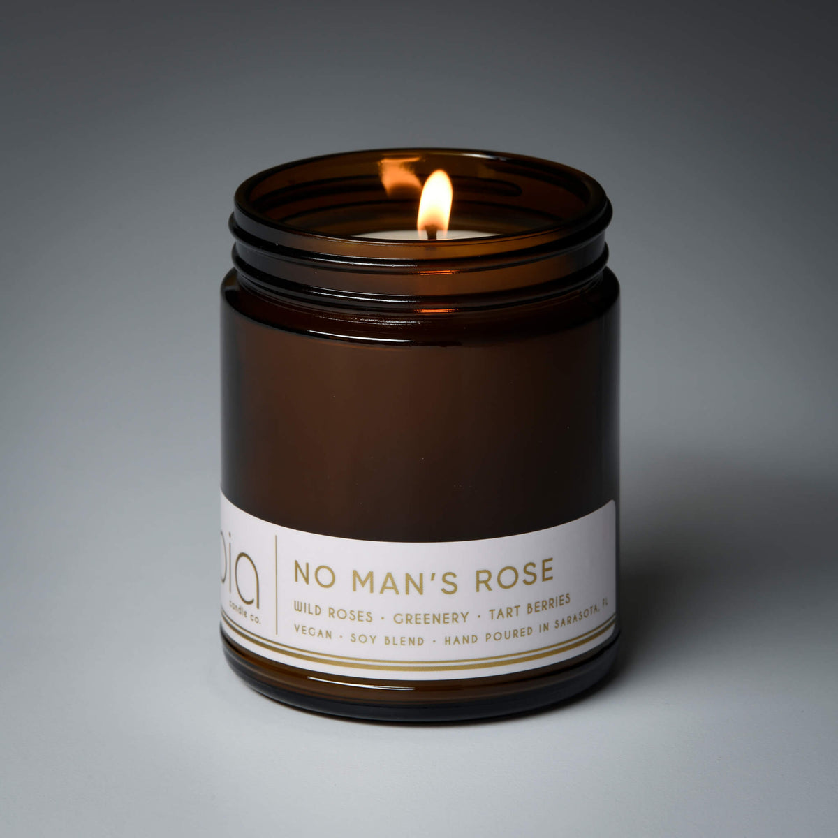 Brown amber candle jar with lit wick and white label panel