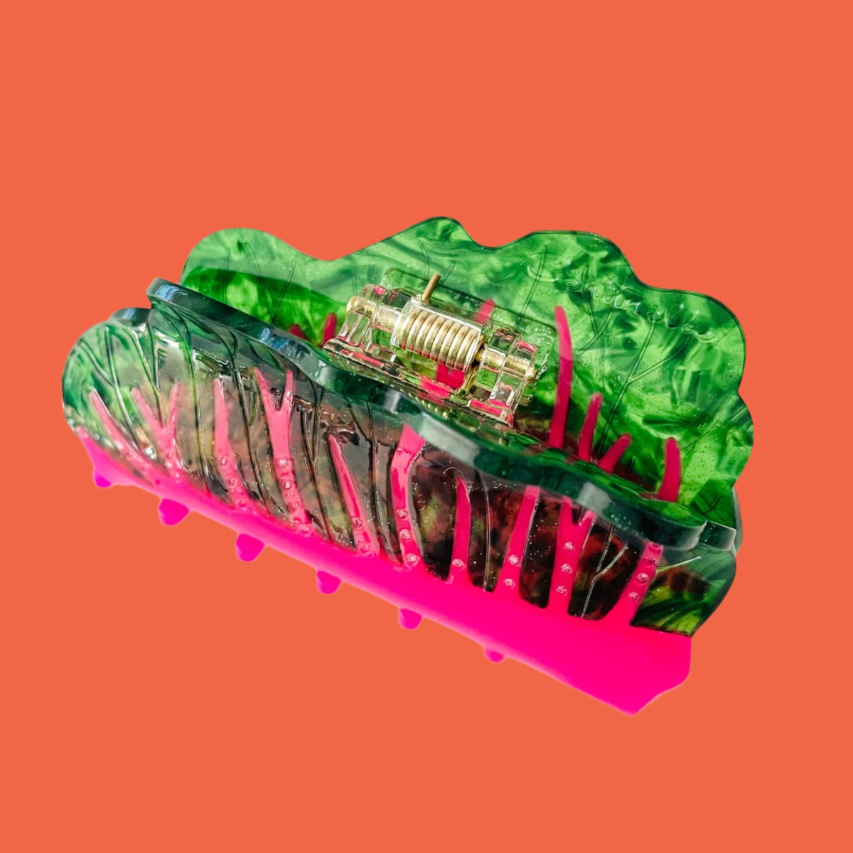 Green translucent hair claw with metal hinge bar, pink base, and comb teeth
