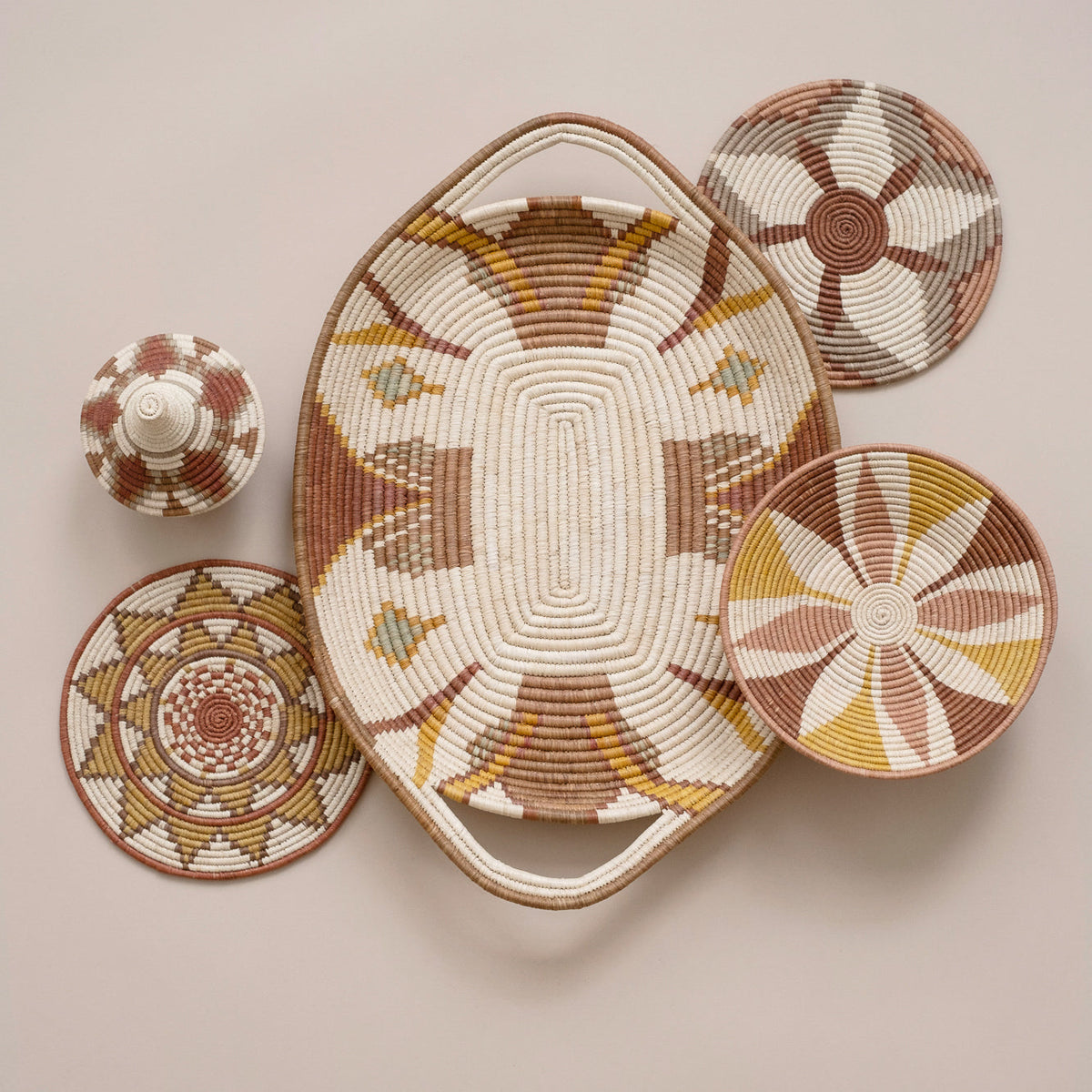 Large woven tray with radial sunburst pattern and matching round coasters in warm earth tones