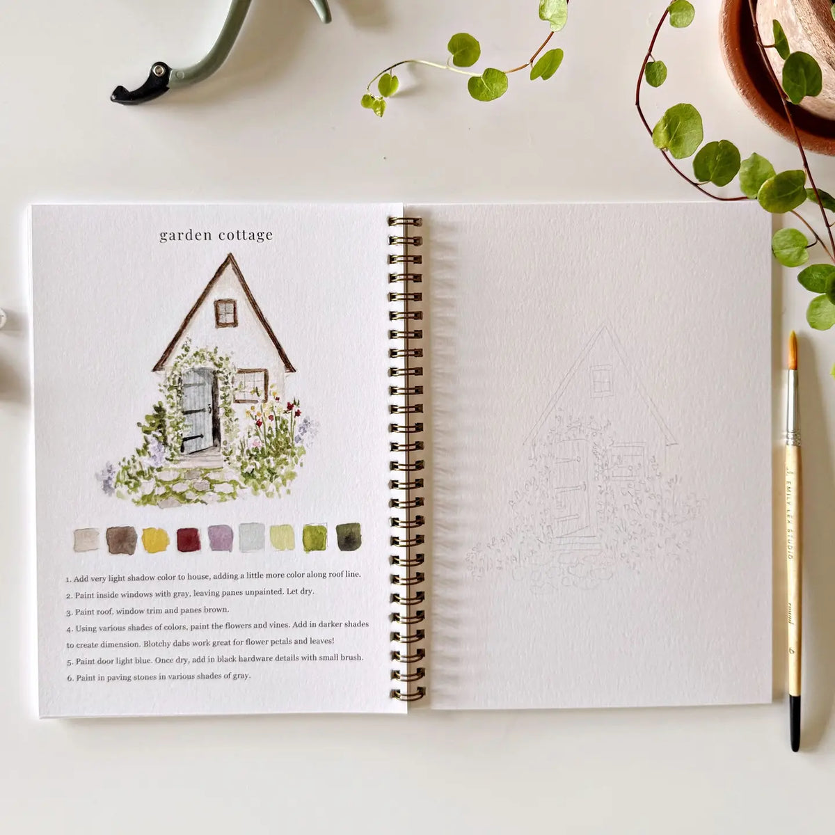 Open Garden watercolor workbook with garden cottage house illustration and faint pencil layout
