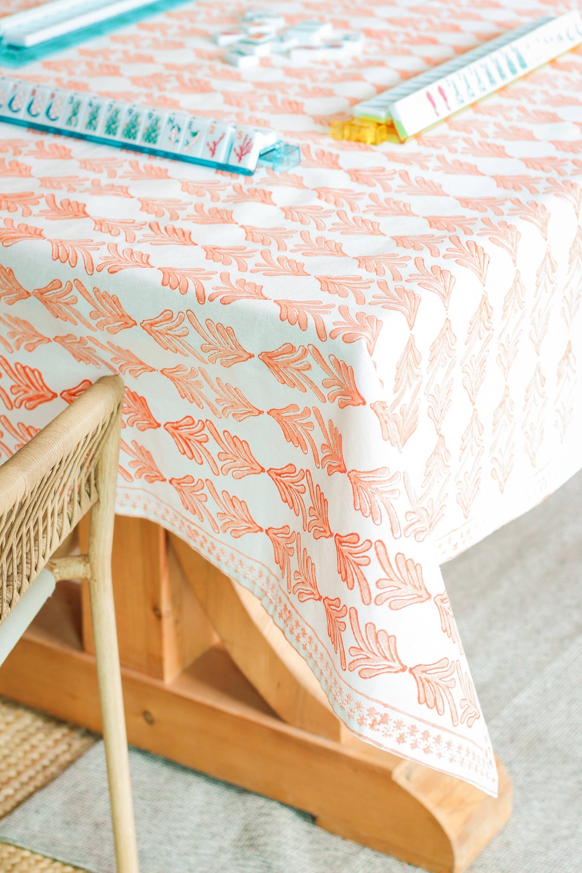 Orange leaf-print table throw with teal border trim, corner draped over table