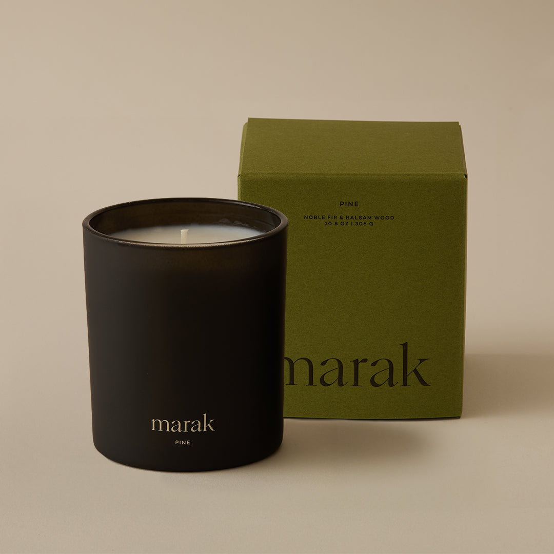 Black marak candle jar with flame beside green marak candle box