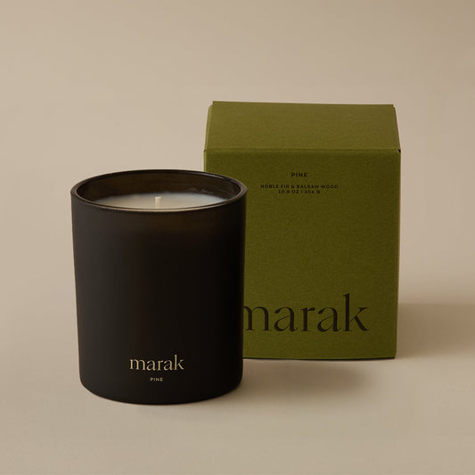 Black marak candle jar with flame beside green marak candle box