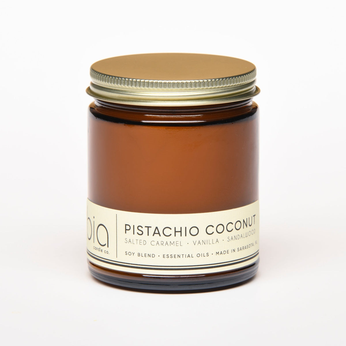 Amber glass jar candle with flat metal lid and printed cream label