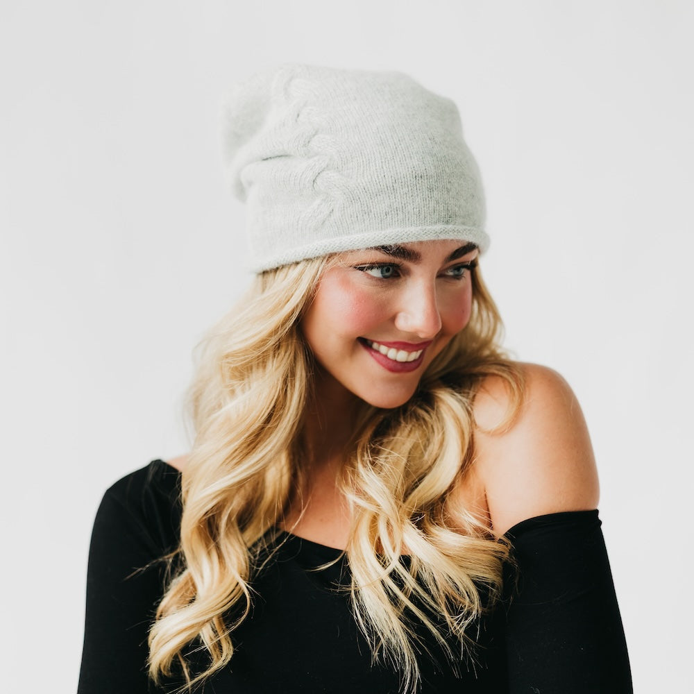 Light gray cashmere beanie with rolled edge cuff and small front pin detail.