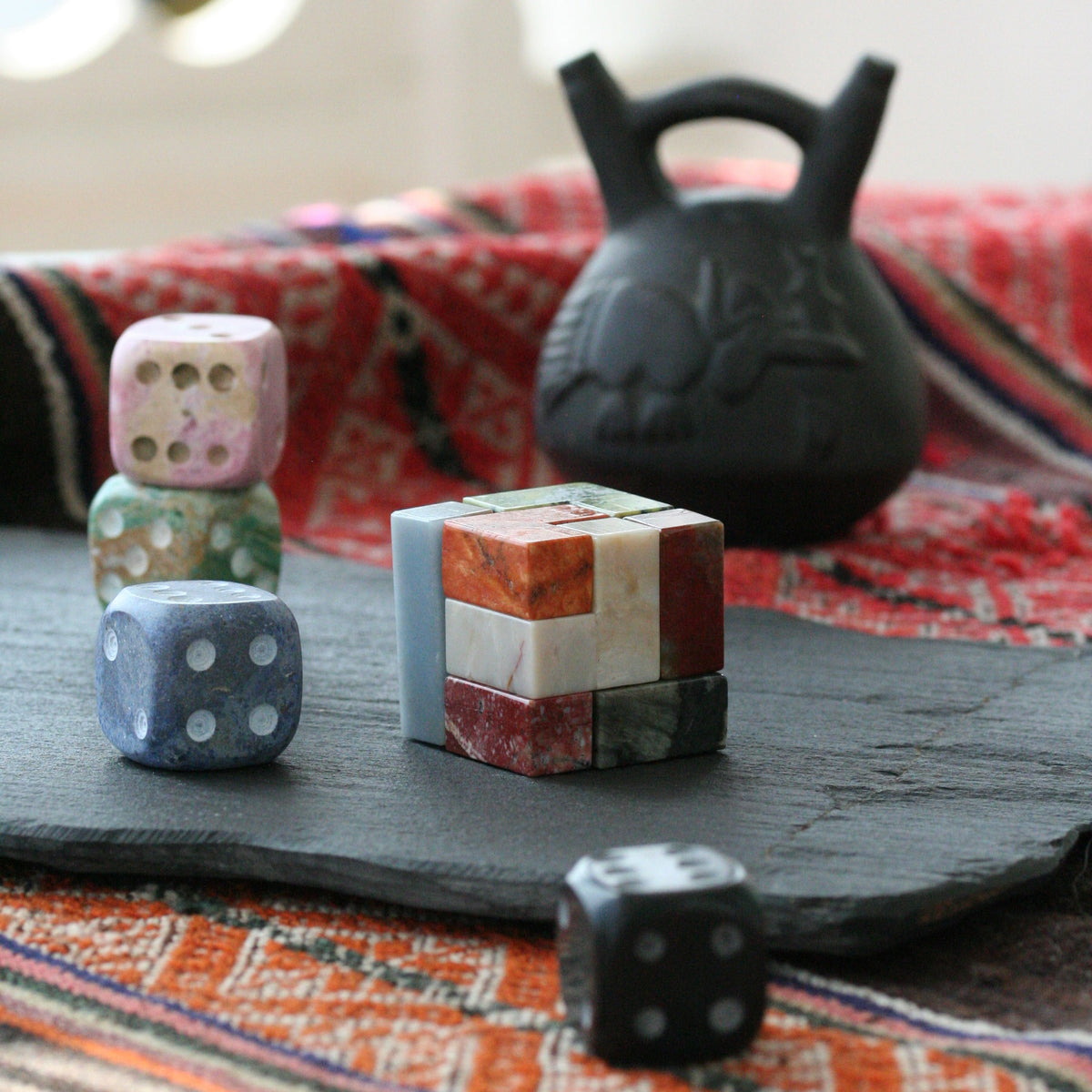 Gemstone cube puzzle with small multicolor cubes on a table next to dice.