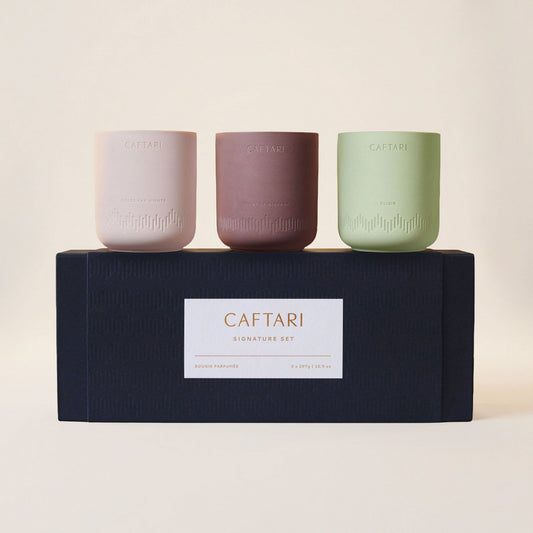 Signature gift set of three Caftari candles in pink, brown, and sage on a dark box