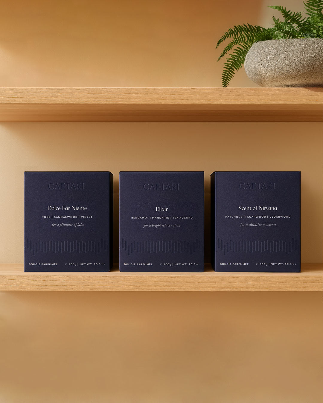 Three Caftari candle boxes on a shelf: Dolce Far Niente, Elixir, and Scent of Nirvana
