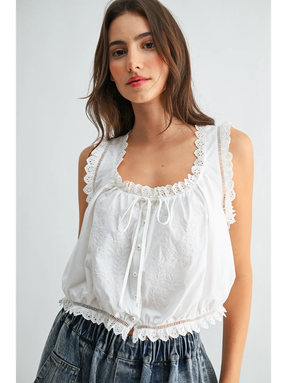 White cotton top with embroidered lace trim, tie neckline, button front and scalloped hem