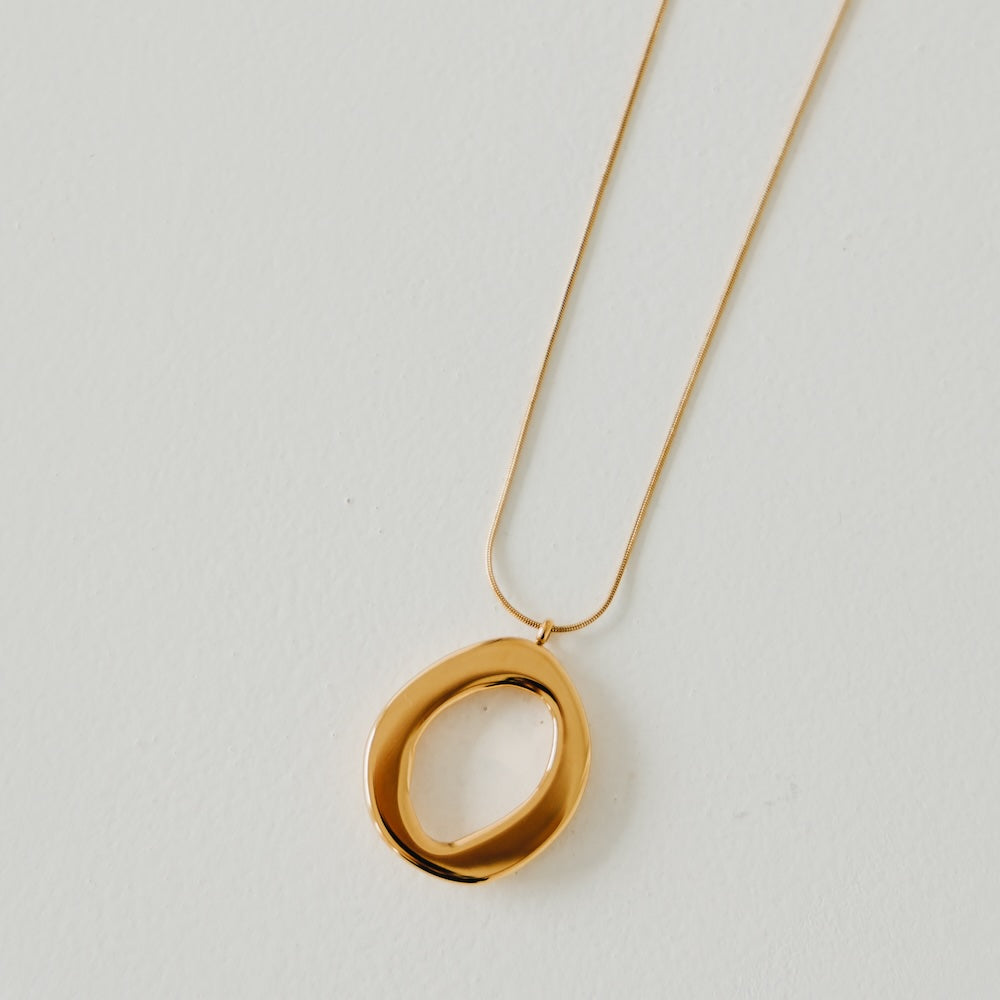 Gold open circle pendant necklace, close-up of chain and oval ring
