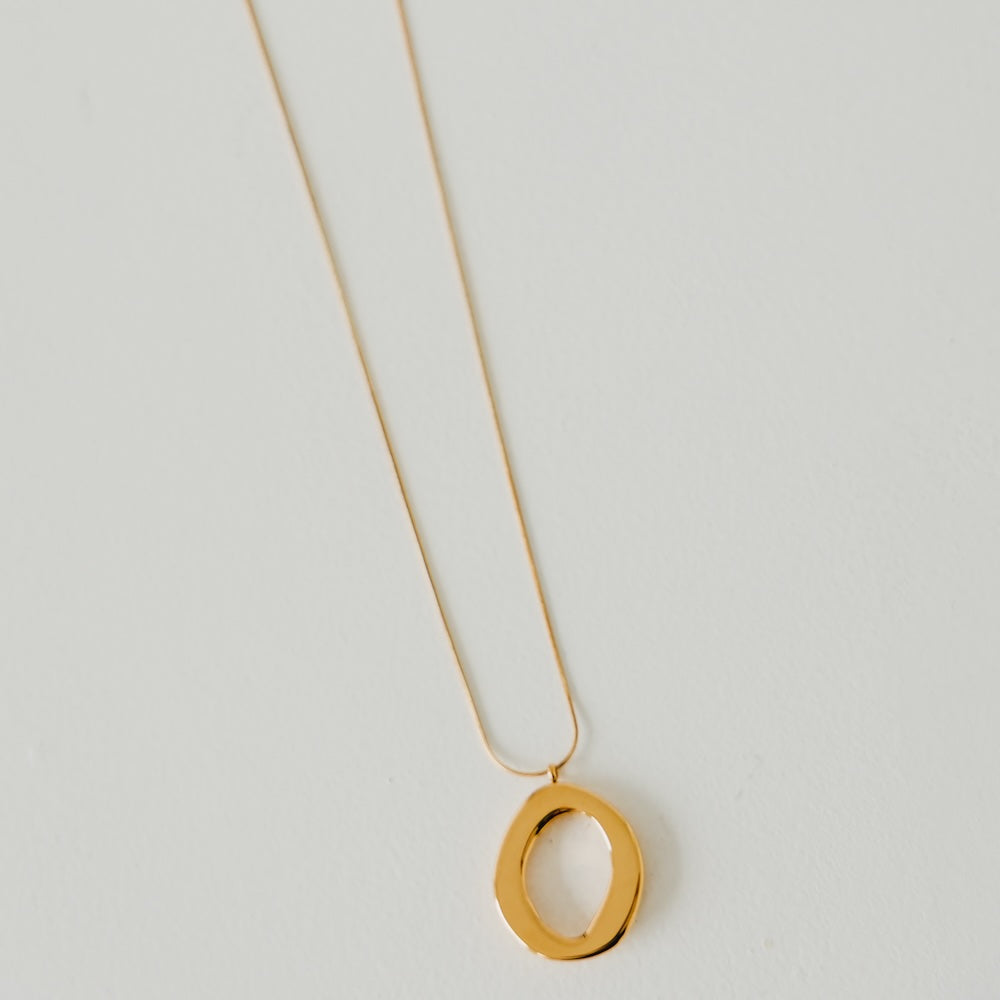 Gold open-circle pendant necklace close-up with oval ring detail