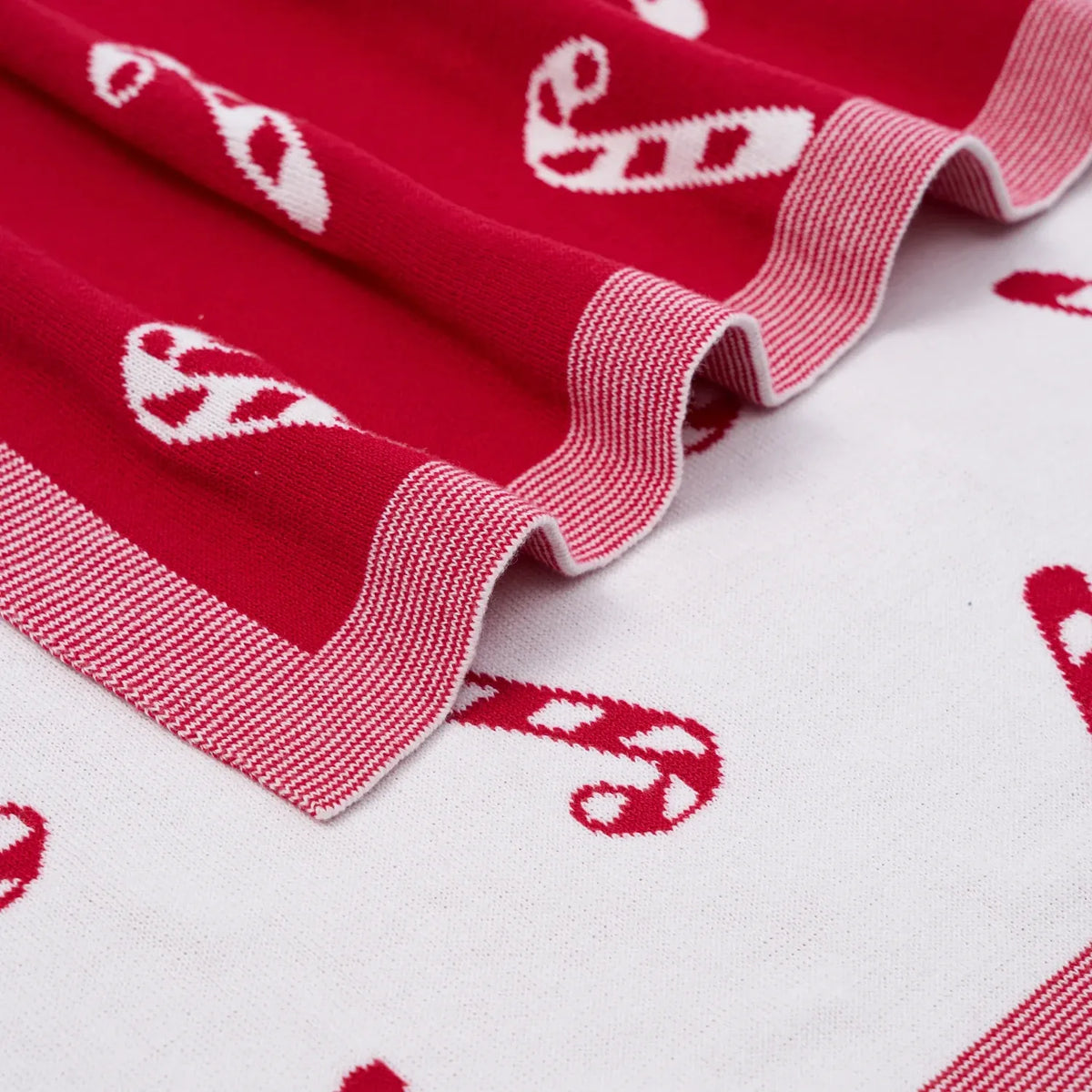 Close-up of red knit blanket edge with white striped trim and candy cane motifs