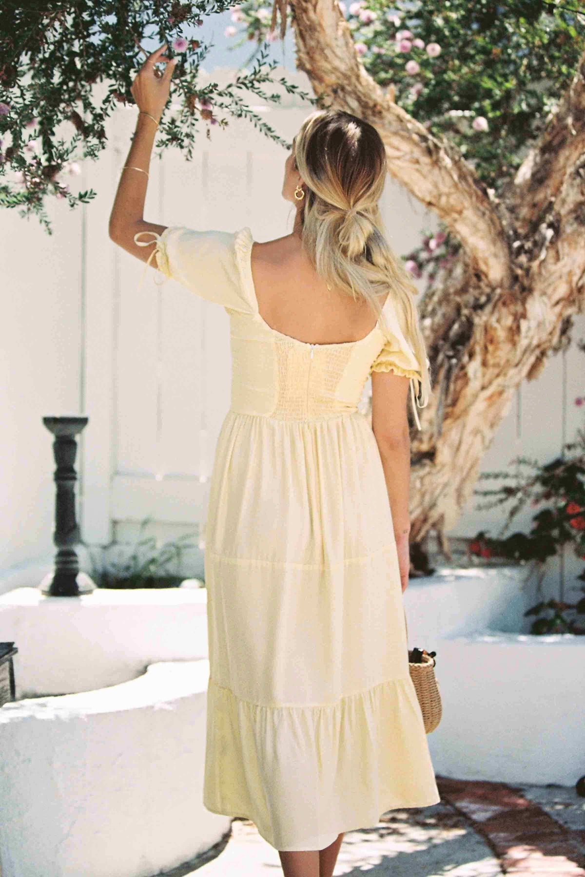 Soft yellow silk midi dress with low open back, puff sleeves, and tiered skirt