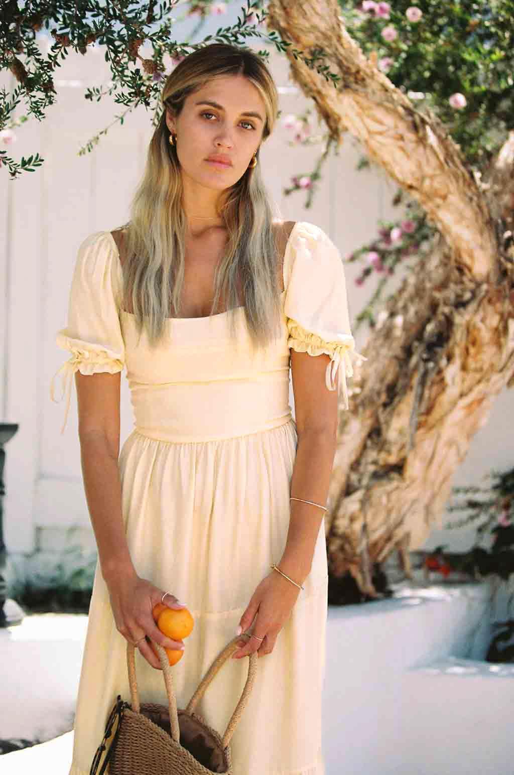Soft yellow silk midi dress with square neckline, puff sleeves, and tiered skirt