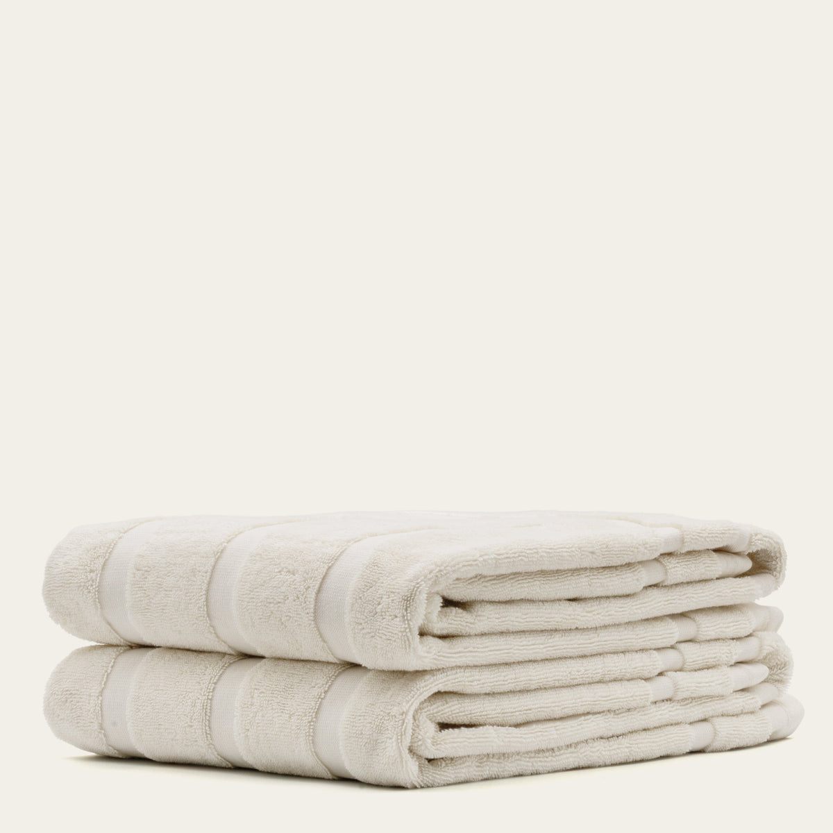 Cream cotton towels with ribbed stripe bands, folded and stacked