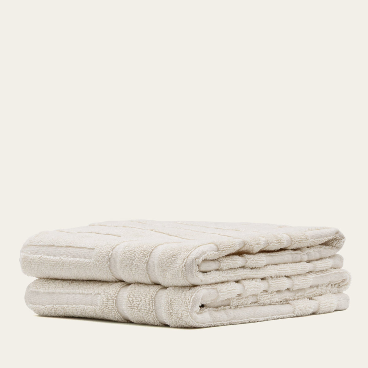 Off-white cotton towel stack, looped terry with stitched border bands