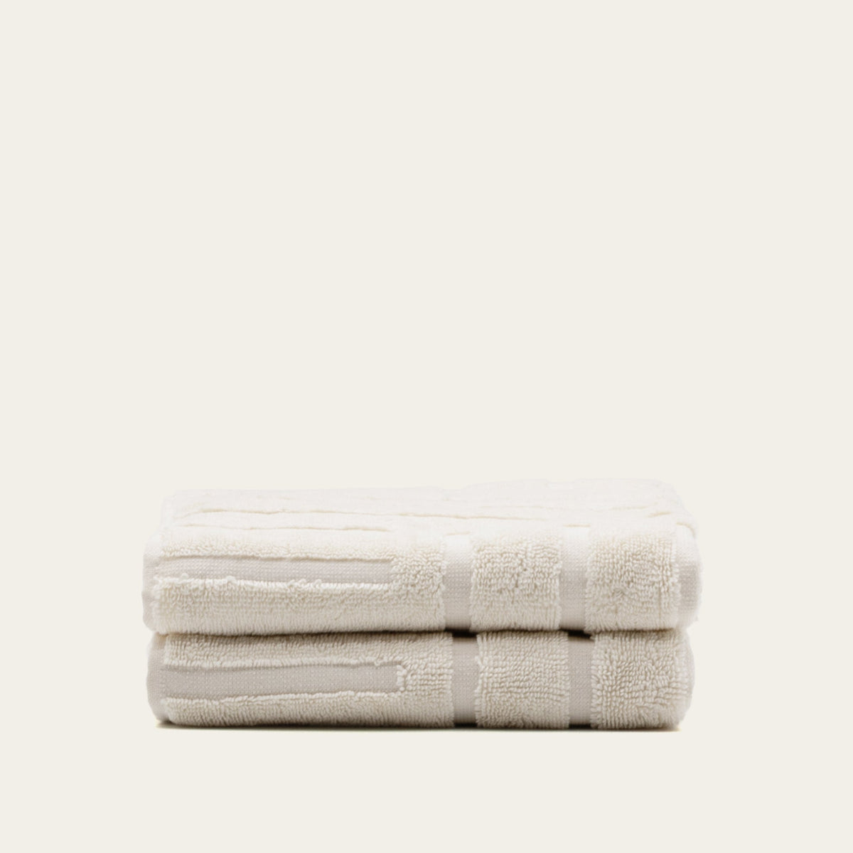 Rolled white cotton towels with subtle pattern bands, bundled together