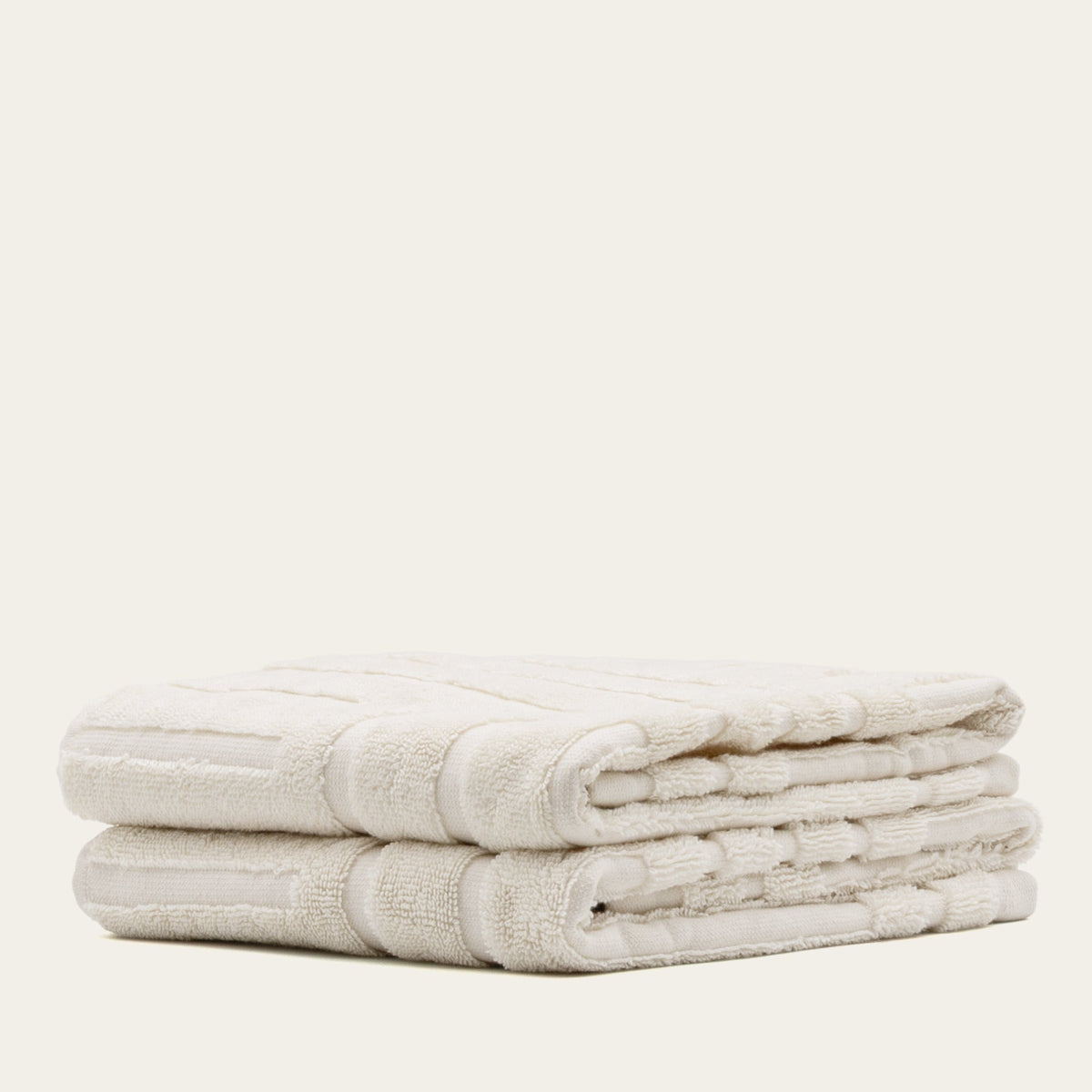 Cotton towels, white with textured border stripes, folded in a stack