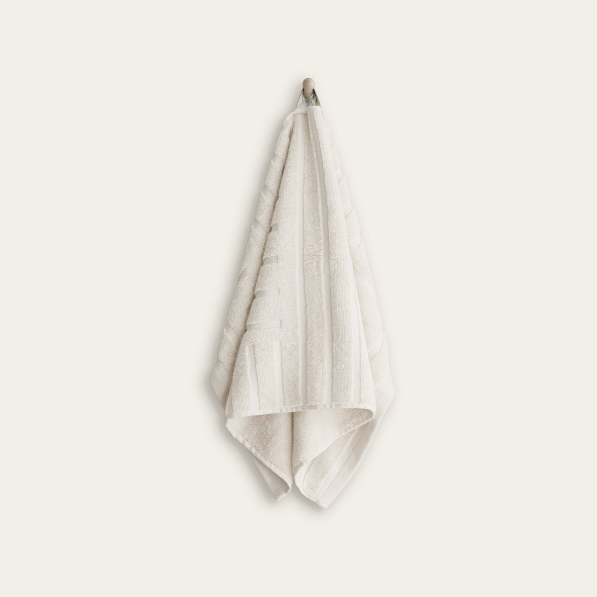 White cotton hand towel folded and hanging, plush terry edge visible