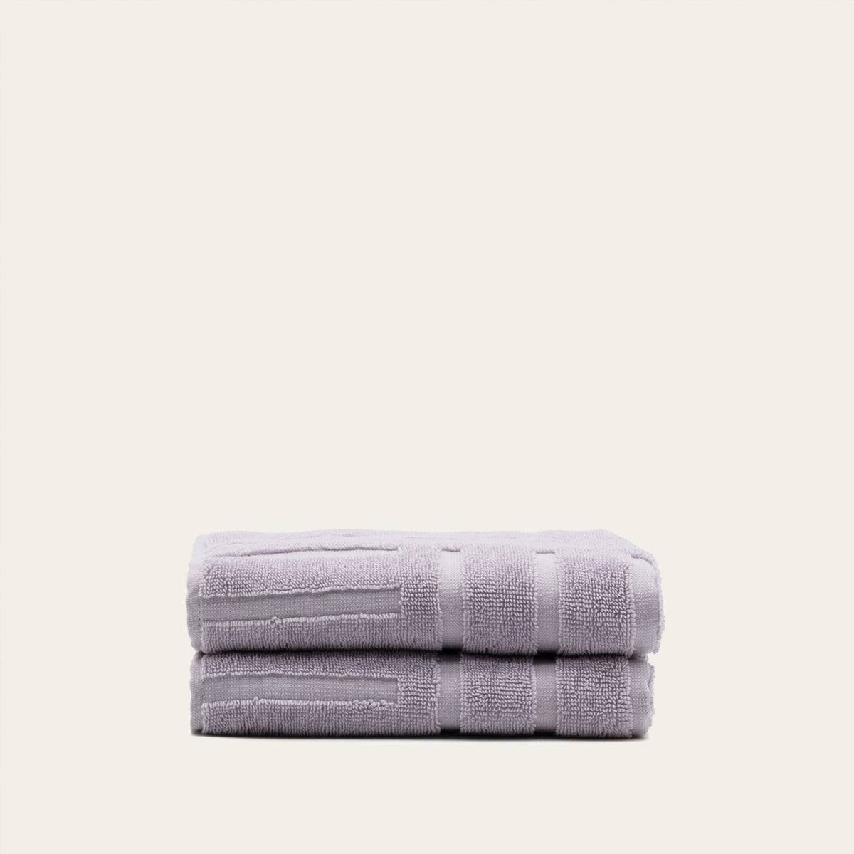 Two lilac cotton towels folded neatly with visible stitched border bands