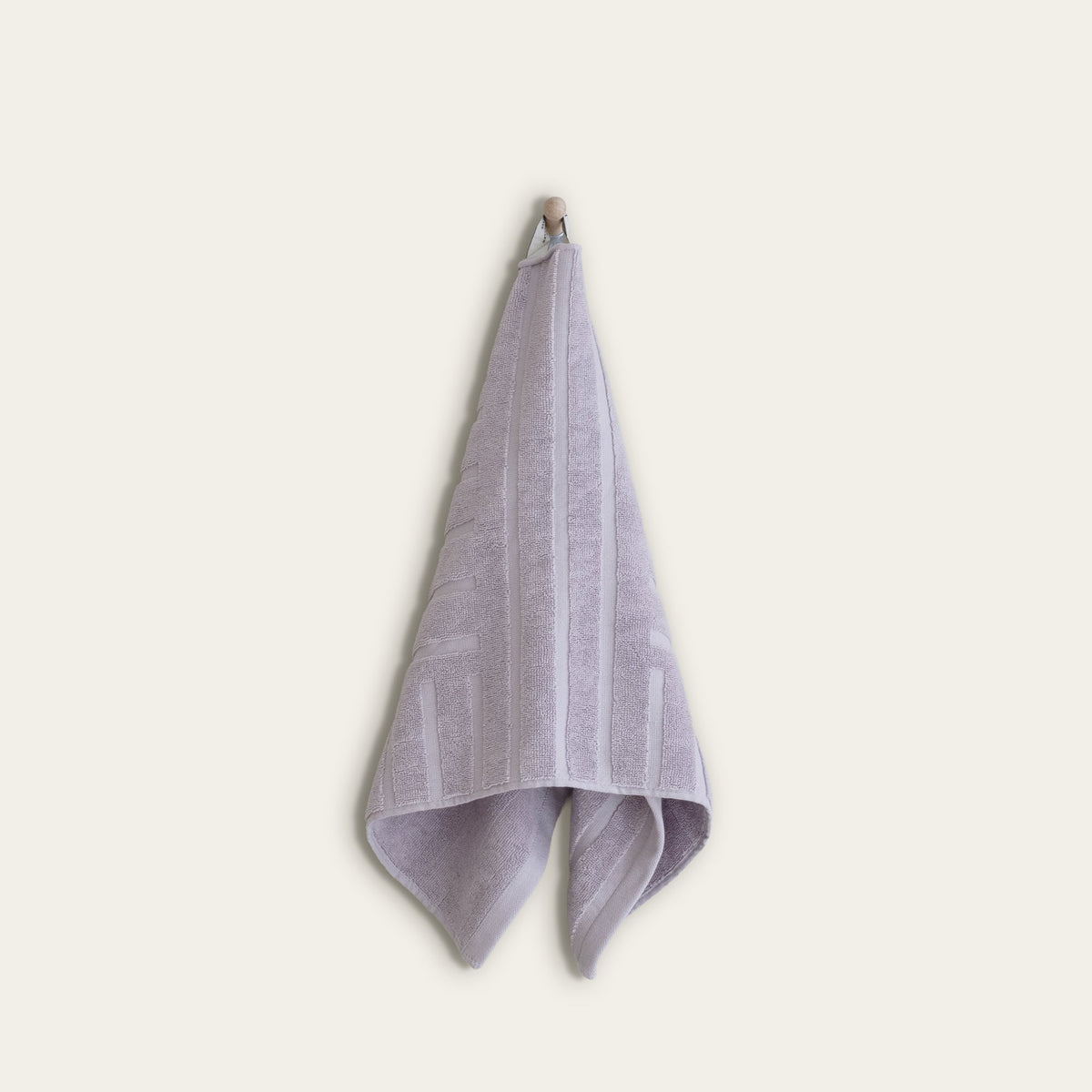 Lilac cotton towel hanging with subtle stripe-and-block geometric design