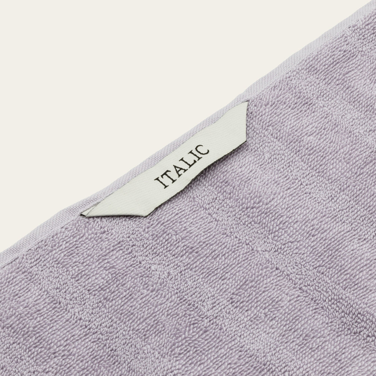 Lilac terry cotton towel close-up with woven edge and ITALIC label