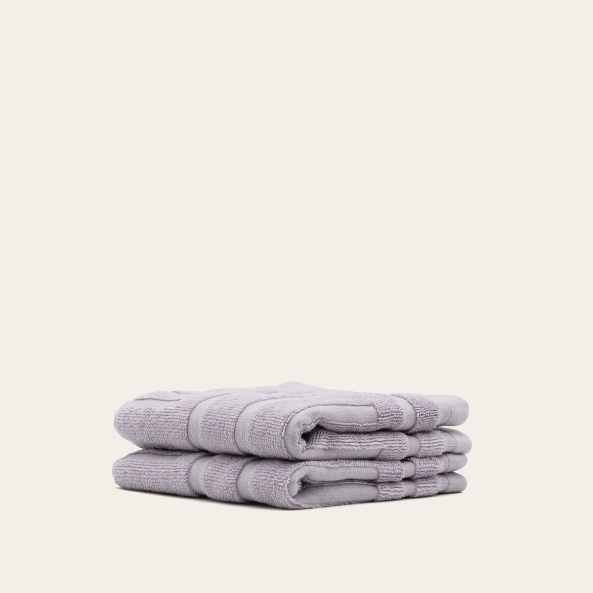 Three lilac cotton towels stacked and folded with wide stitched bands