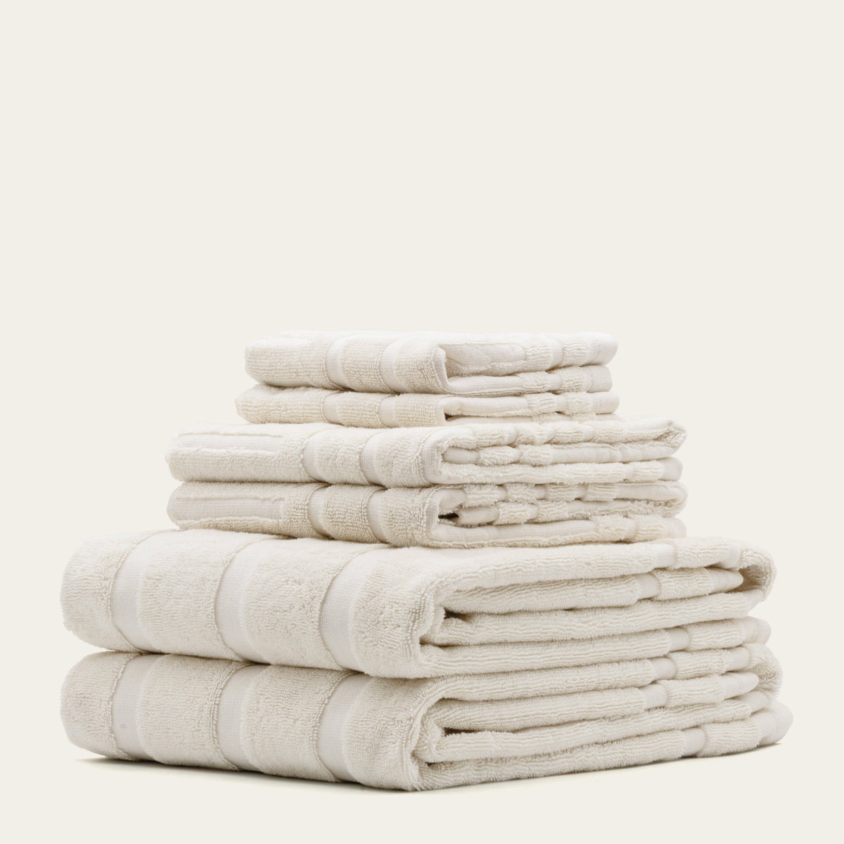 Cream cotton towel stack with multiple folds and woven stripe bands