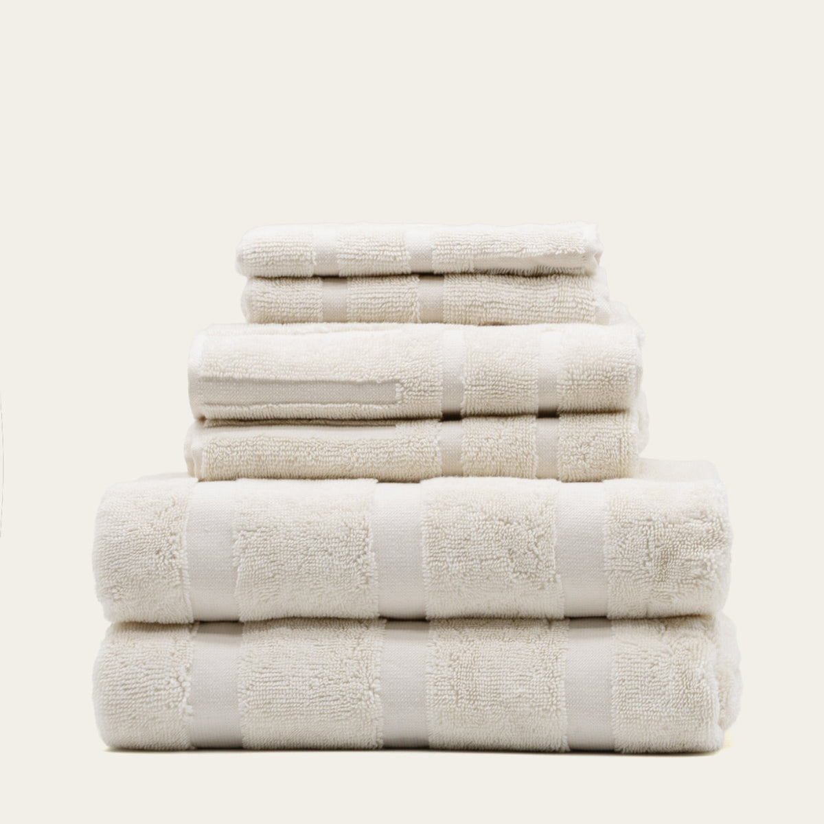Stack of white cotton towels with patterned bands, folded for bath use