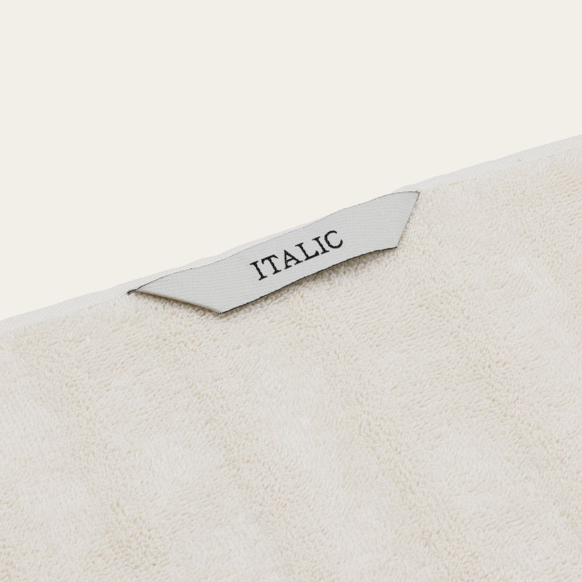 White cotton towel with woven “ITALIC” label, visible corner edge