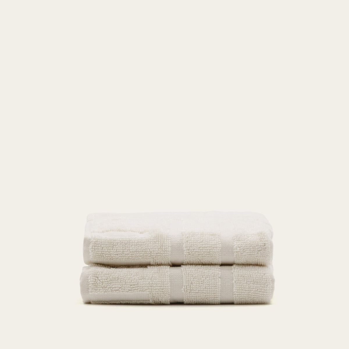 Cream cotton towels, two folded stacks with ribbed stripe bands