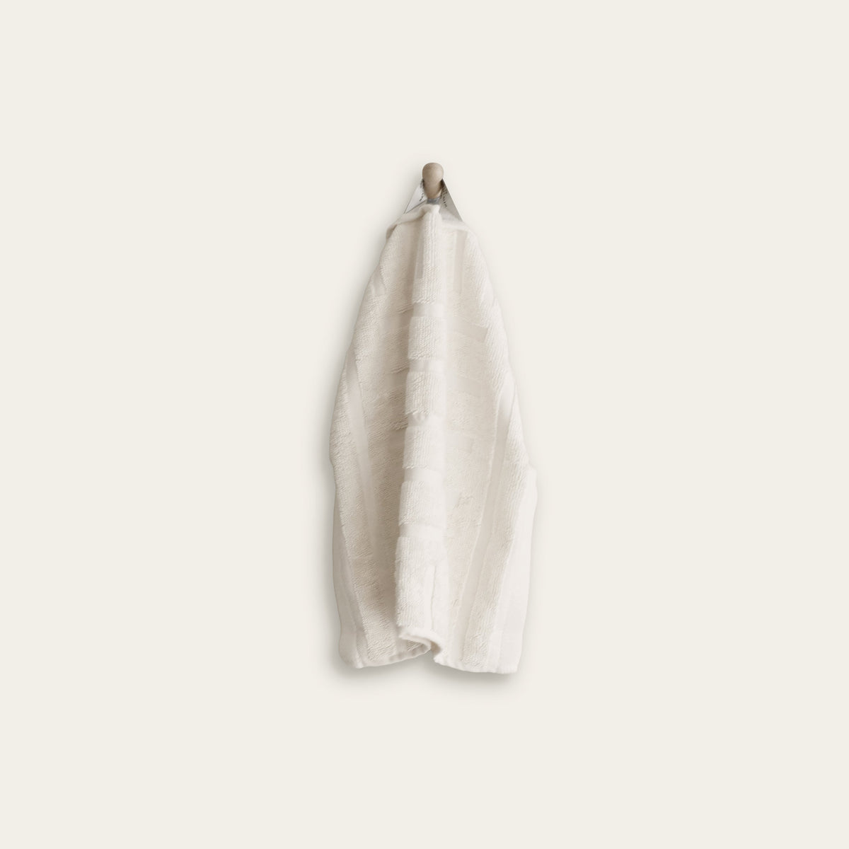 White cotton towel hanging on a looped strap, neatly folded