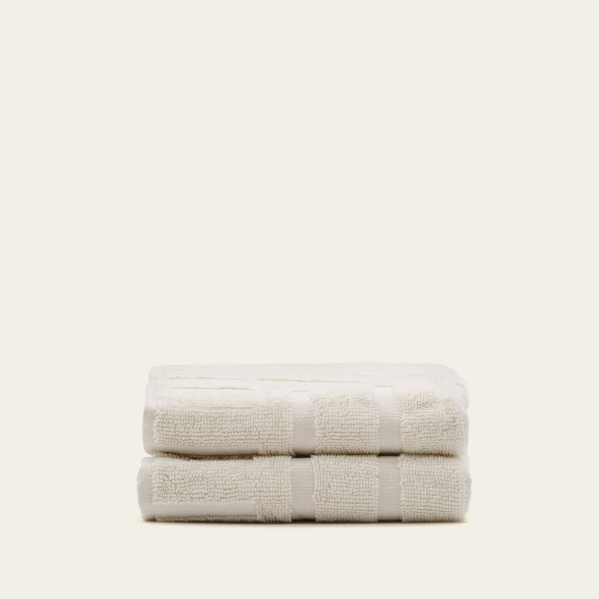 Off-white cotton towel with stitched border band, neatly folded in half