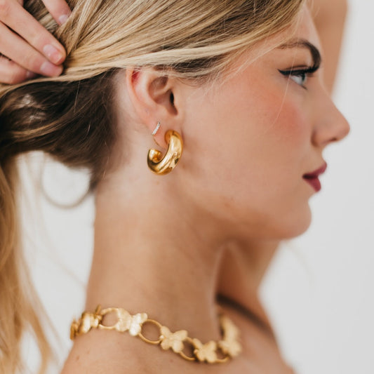 Gold reversible hoop earrings worn with double-hoop curve and spherical accents