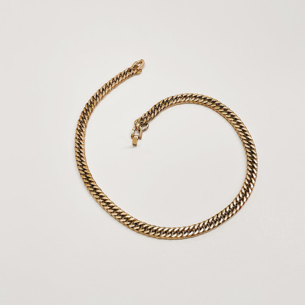 Gold Cuban chain necklace flat lay, chunky Cuban-style links with clasp detail