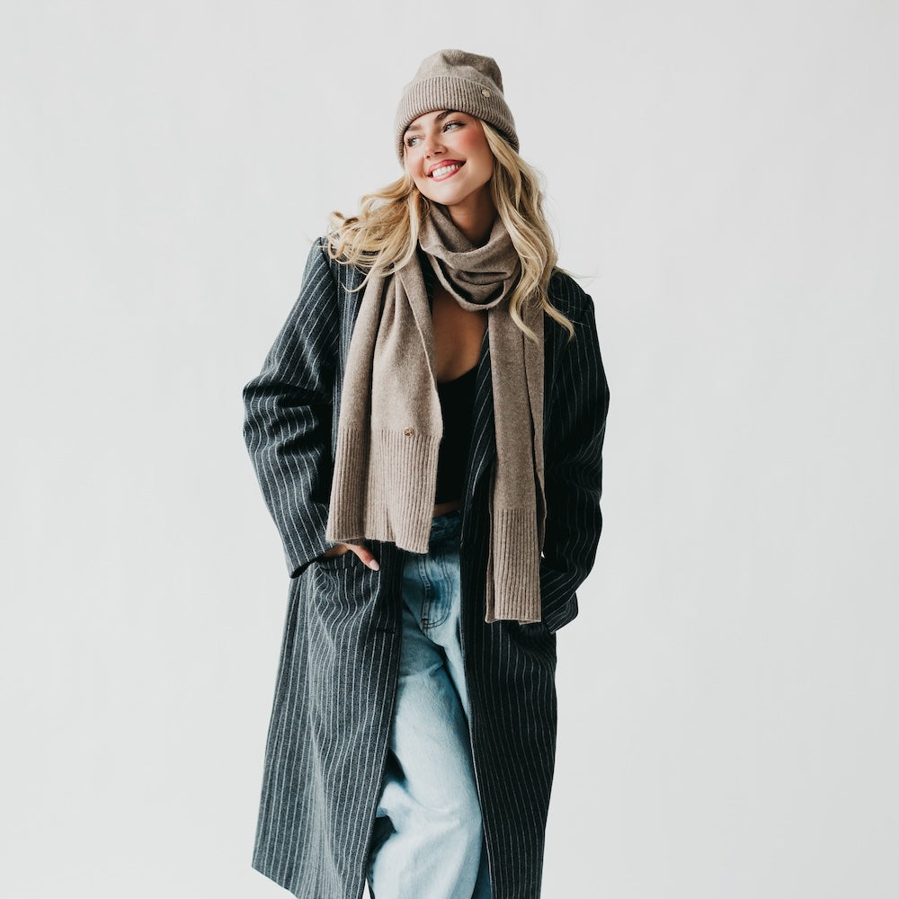 Mocha cashmere wrap scarf and ribbed knit beanie set, draped over shoulders