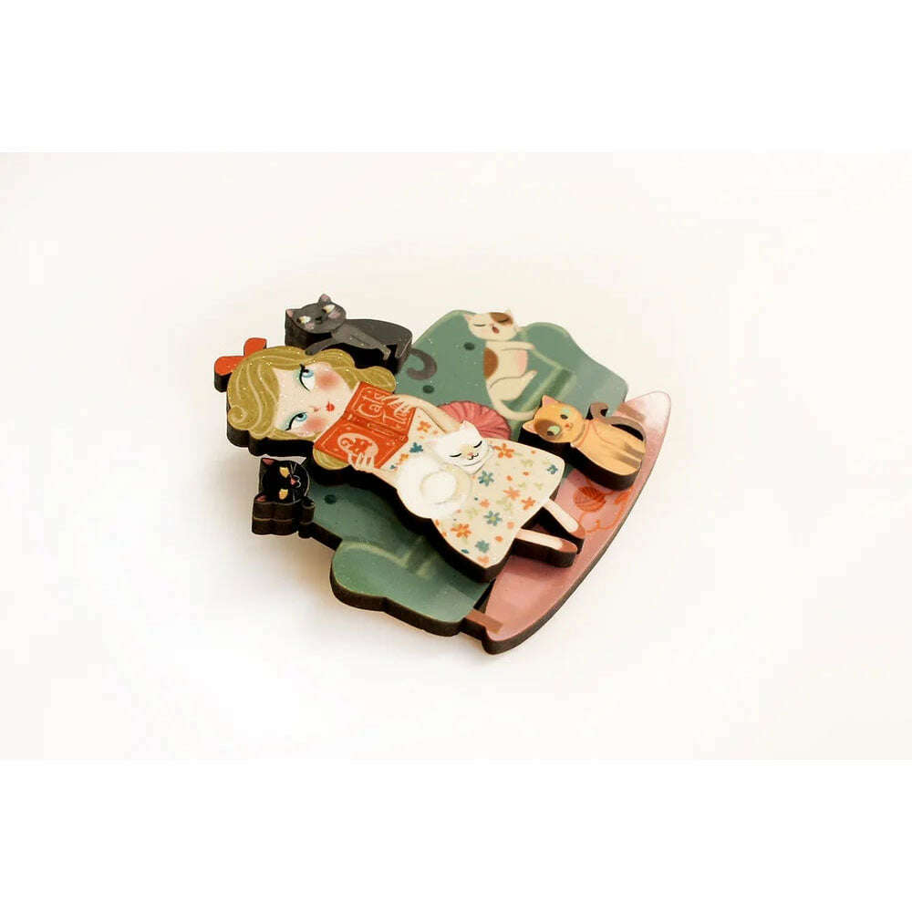 Cat lover brooch, angled view: girl reading orange book with cats on rocking chair