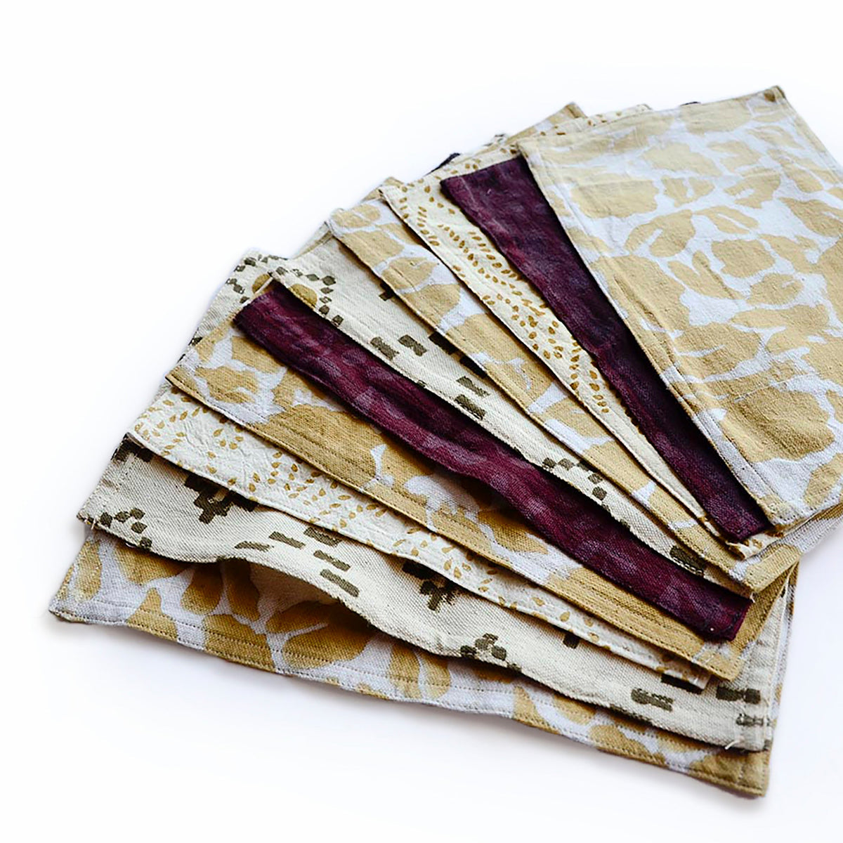 Stack of folded cotton towels in beige, cream, and deep maroon patterned fabric