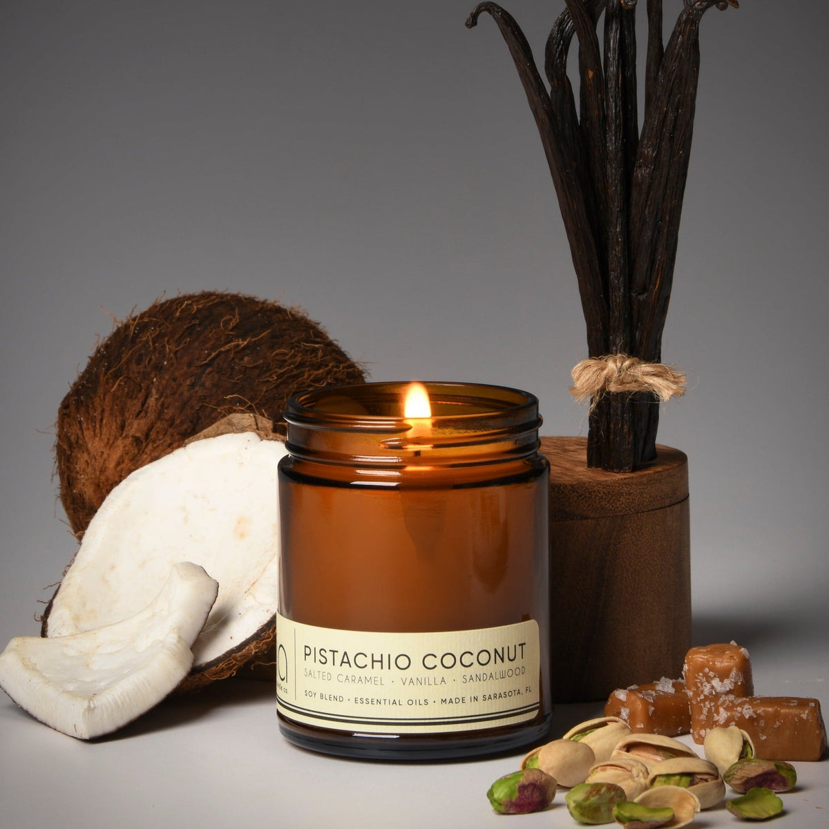 Lit amber jar candle with cream label and nearby coconut and nut decor