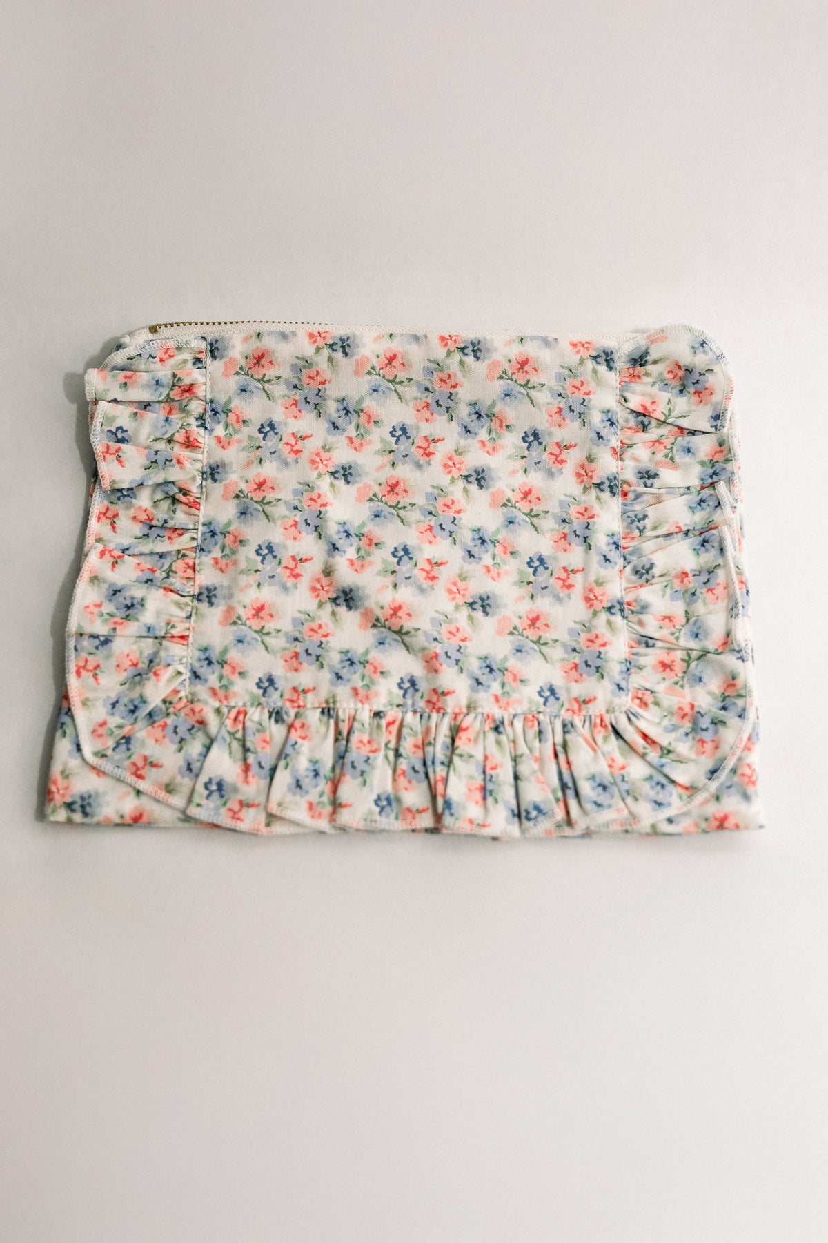 Floral ruffle zipper pouch with gathered front and light blue backing, coral and blue flowers