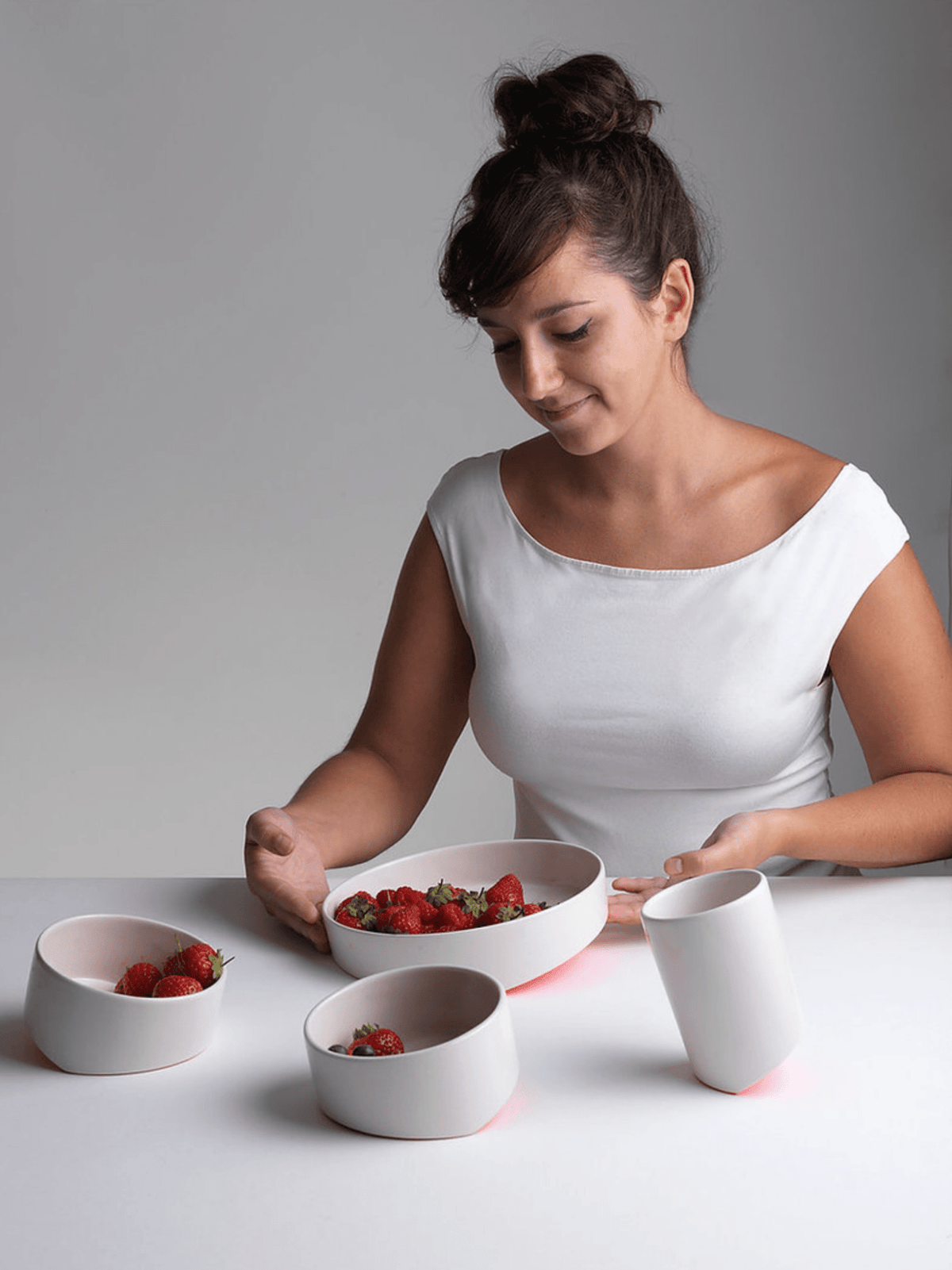 Ceramic bowl and cups set on table, with berries and a hand pouring
