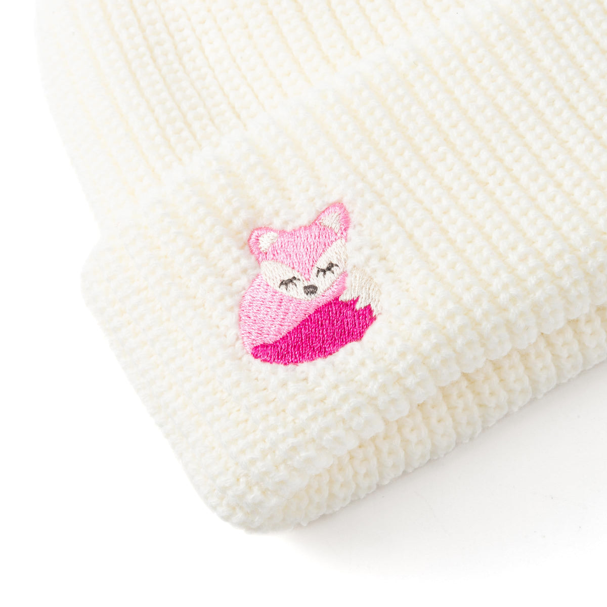 Close-up of the pink fox patch on a white knitted beanie cuff
