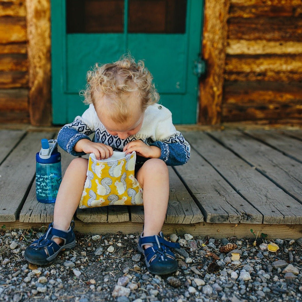 Reusable snack bag for kids with yellow floral print, worn by a toddler