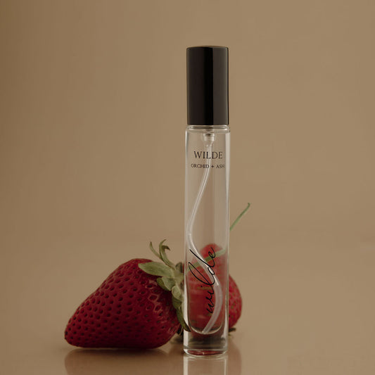 Travel perfume spray bottle with WILDE ORCHID + ASH label, clear glass and black cap