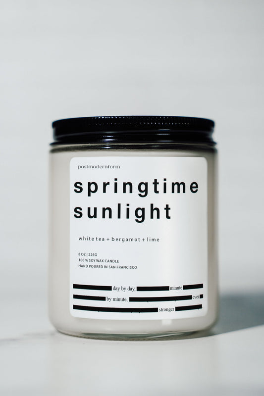 Glass candle jar with black lid, springtime sunlight label and white tea + bergamot + lime