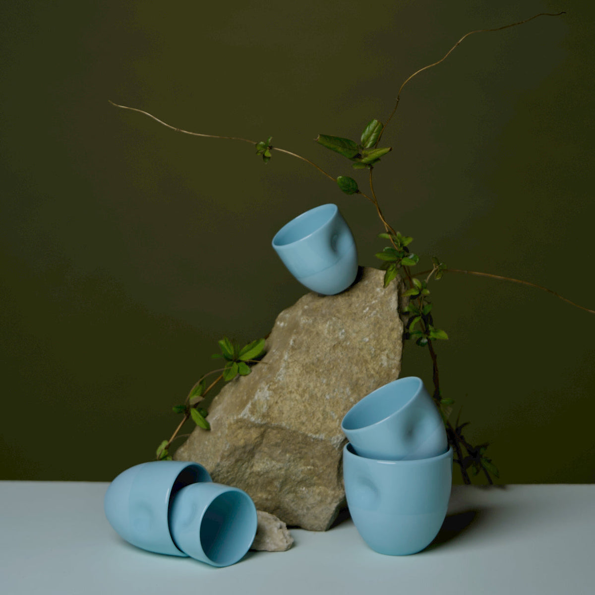 Denim blue thumbprint porcelain cup with rounded handleless design; three cups visible